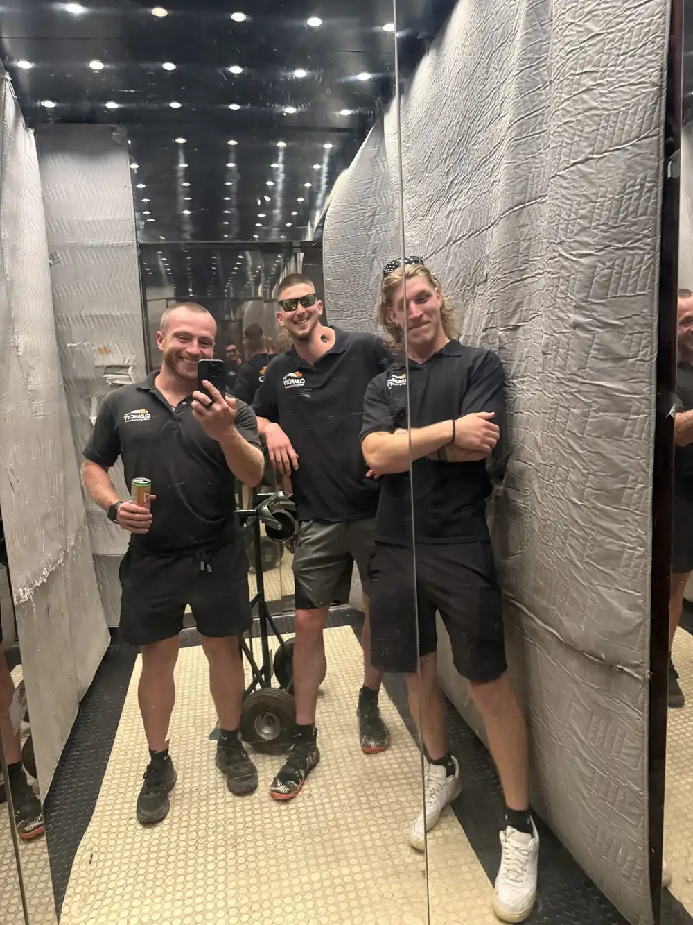 Three crew members in a freight elevator with a dolly, on a commercial job
