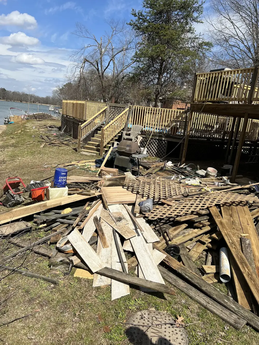 Boards and lumber from a torn-out deck piled on a lawn