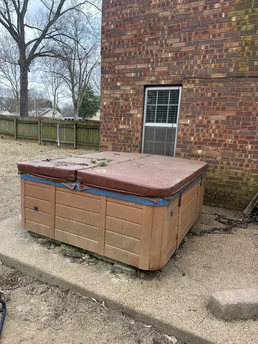 Before: an old hot tub sitting against a brick house