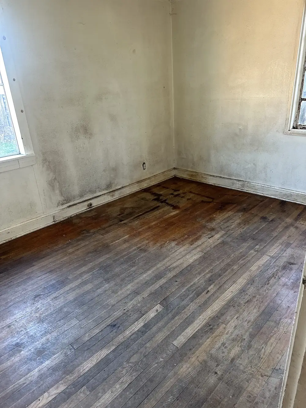 An empty room with bare floors after a house cleanout