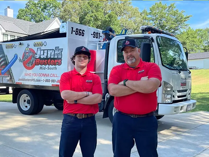 Two Junk Busters crew members in red shirts in front of their box truck
